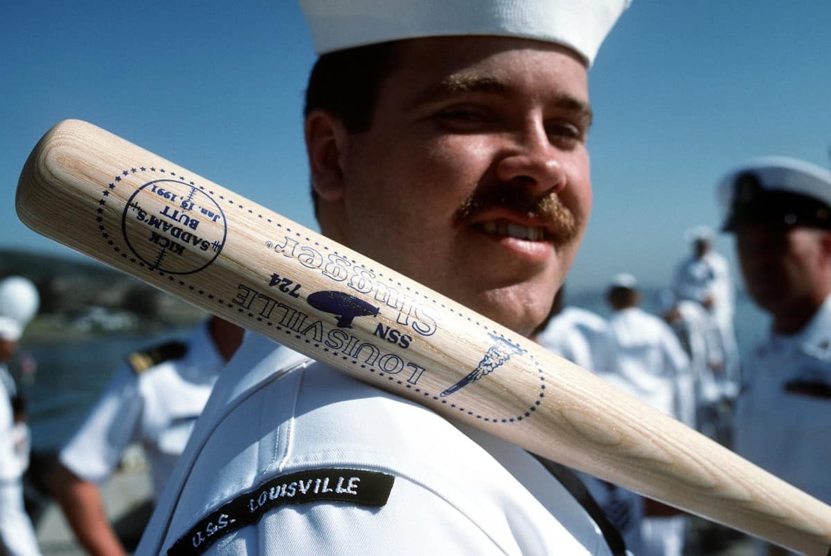 A sailor assigned to the nuclear-powered attack submarine USS Louisville holds a Louisville Slugger baseball bat commemorating the submarine's role in the Persian Gulf war. Chinese investors purchased the brand that makes Louisville Slugger bats in 2018. 