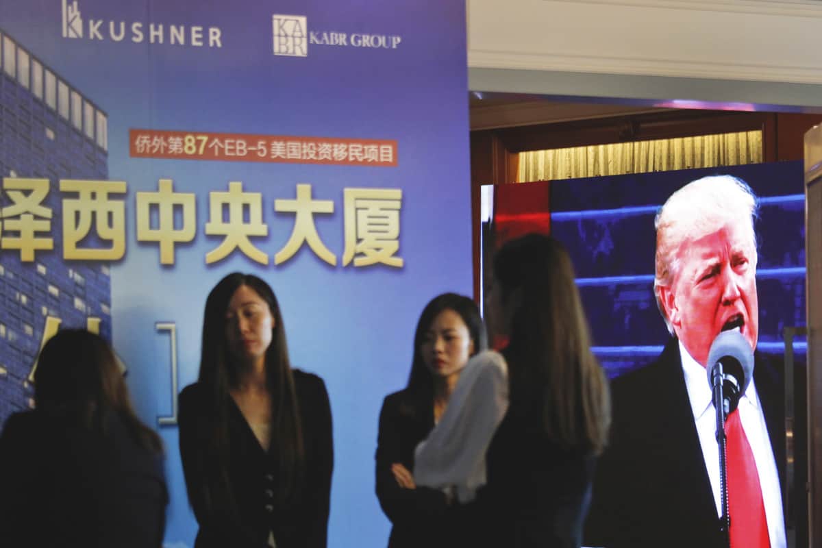 A projector screen shows a footage of President Trump as workers wait for investors at a reception desk during an event promoting EB-5 investment in a Kushner Companies development at a hotel in Shanghai, China, Sunday, May 7, 2017